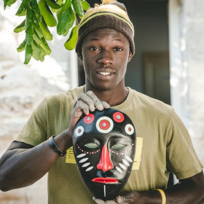 Un ragazzo mostra una maschera dipinta a mano